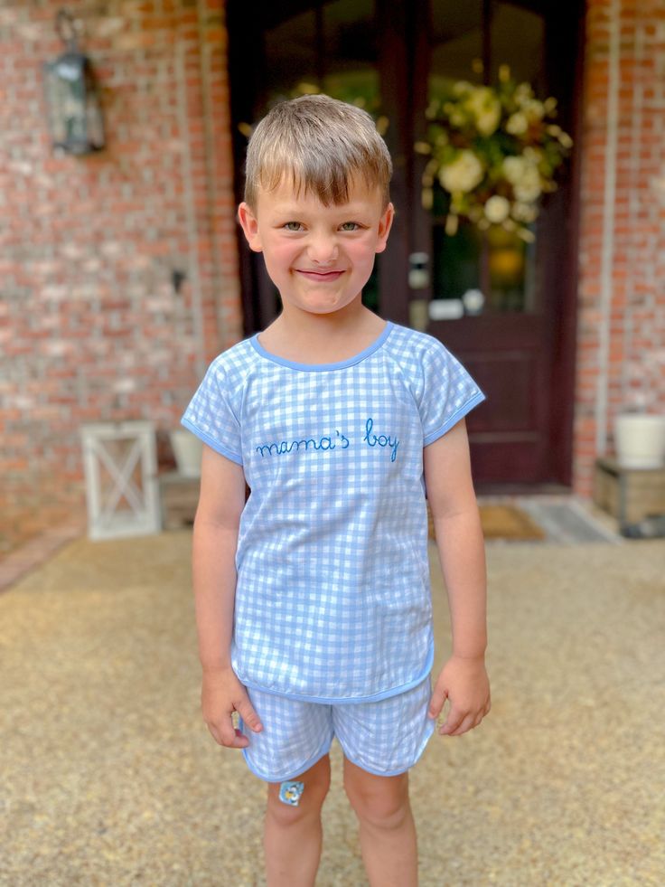 Introducing our Embroidered Baby Blue Gingham Lounge Short Set for Boys – a charming and cozy addition to your little one's sleepwear collection. This adorable set features a classic baby blue gingham pattern, perfect for a timeless and sweet look. The set includes a short-sleeve top and matching shorts, both crafted from soft, breathable fabric to ensure comfort throughout the night. The top is adorned with "mama's boy" hand-embroidered across the chest, adding a heartfelt touch that celebrates Plaid Cotton Sets For Sleepover, Plaid Cotton Sleepover Sets, Cotton Gingham Loungewear Sets, Gingham Cotton Loungewear Sets, Gingham Cotton Sleepwear For Sleepover, Gingham Cotton Sleepwear For Bedtime, Plaid Cotton Playtime Set, Cute Plaid Cotton Sets, Cute Light Blue Cotton Sleepwear