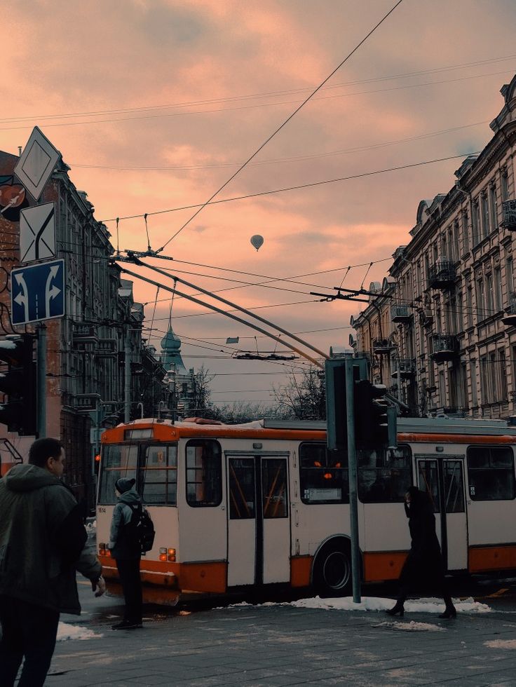 an orange and white bus on street next to buildings