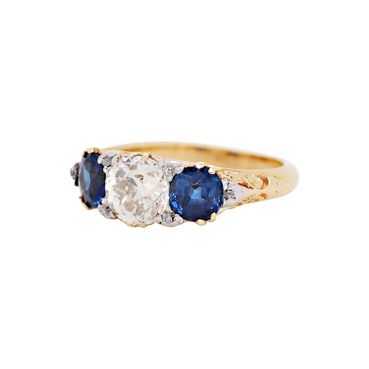 Hand carved Late Victorian three stone ring set with a 1.41ct old cut diamond and two beautiful blue sapphires on either side with a combined weight of 1.61ct all in open back, claw settings. The centre stone is decorated with four old cut diamonds on each claw. The ring is then finished with a further two old cut diamonds in white metal on either side of the sapphires, all set on top of a beautifully intricate scroll design yellow gold mount. Stamped 18. UK finger size 'J'. Three Stone Ring Settings, Bezel Set Diamond Ring, Three Stone Ring, Antique Blue, Top Rings, Bezel Set Diamond, Modern Ring, Three Stone Rings, Three Stone