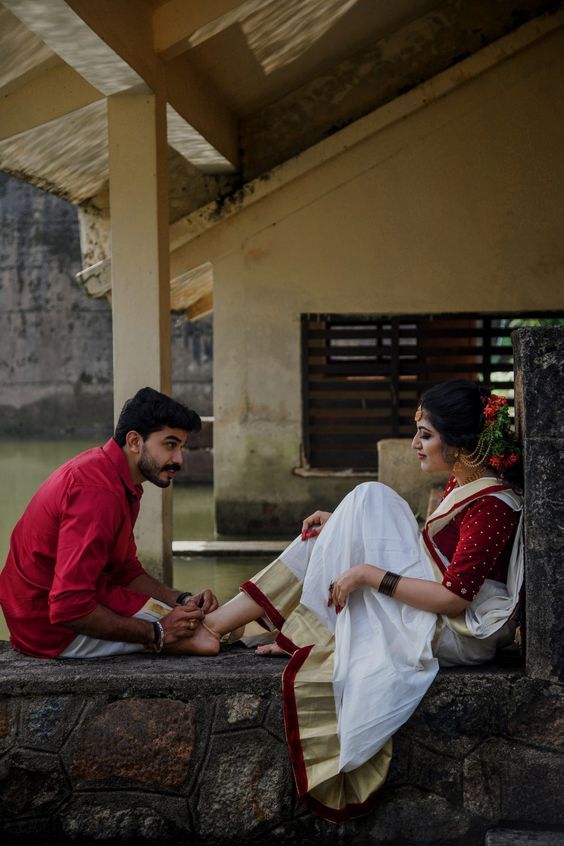 a man sitting next to a woman on top of a stone wall in front of a building