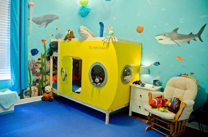 a child's room decorated in blue, yellow and white with shark wallpaper