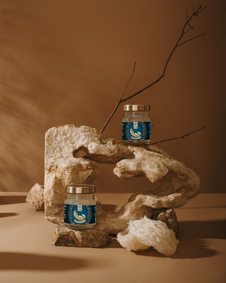 two candles sitting on top of a piece of driftwood next to rocks and branches