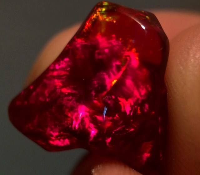 a close up of a red diamond on someone's finger