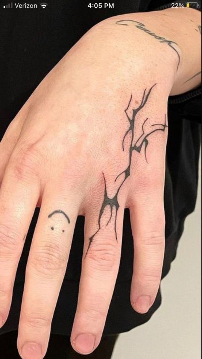 a person's hand with a tree branch tattoo on the middle of their finger