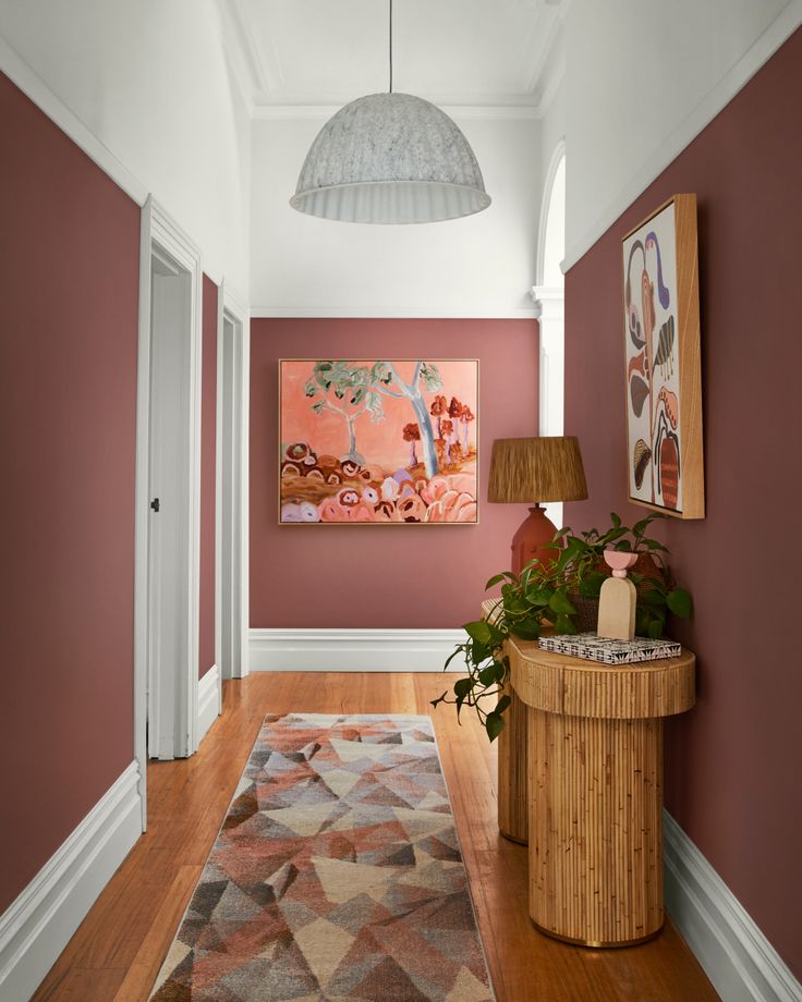 a hallway with pink walls and wooden flooring next to a painting on the wall