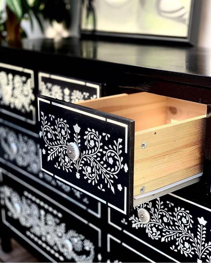 an ornate black and white dresser with drawers