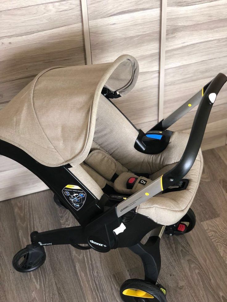 a baby car seat sitting on top of a hard wood floor next to a wall