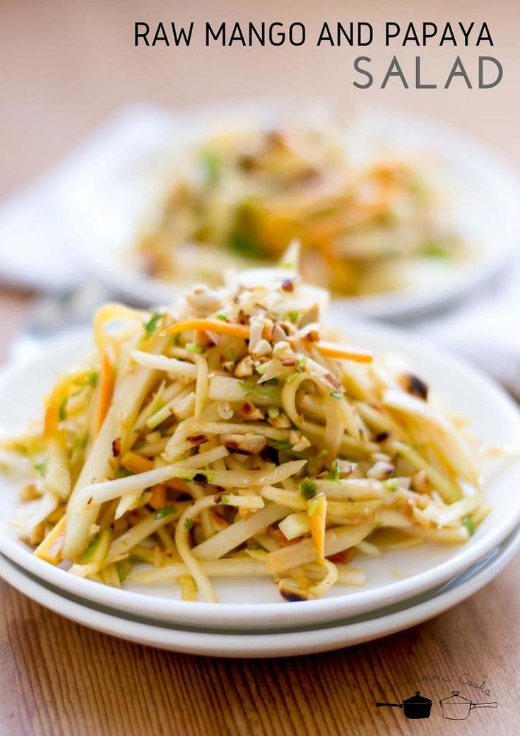 raw mango and papaya salad on a white plate with text overlay that reads raw mango and papaya salad