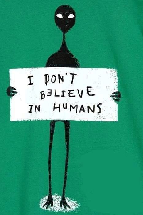 an alien holding a sign with the words i don't believe in humans on it