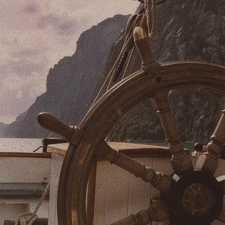 an old ship steering wheel with mountains in the background