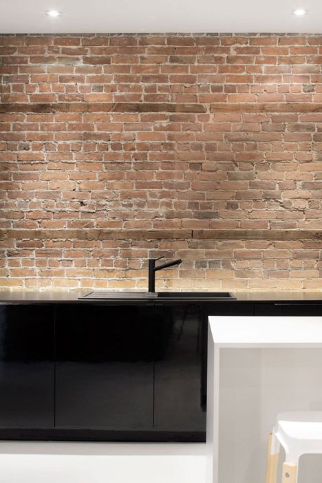 a black kitchen sink sitting next to a white counter top under a wooden brick wall