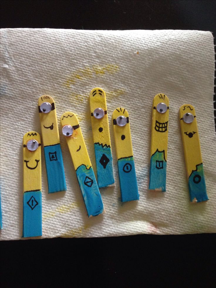 five yellow and blue paper clips with faces drawn on them are lined up in a row