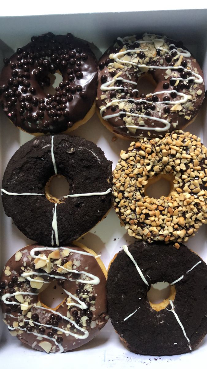 six donuts with chocolate frosting and sprinkles in a box