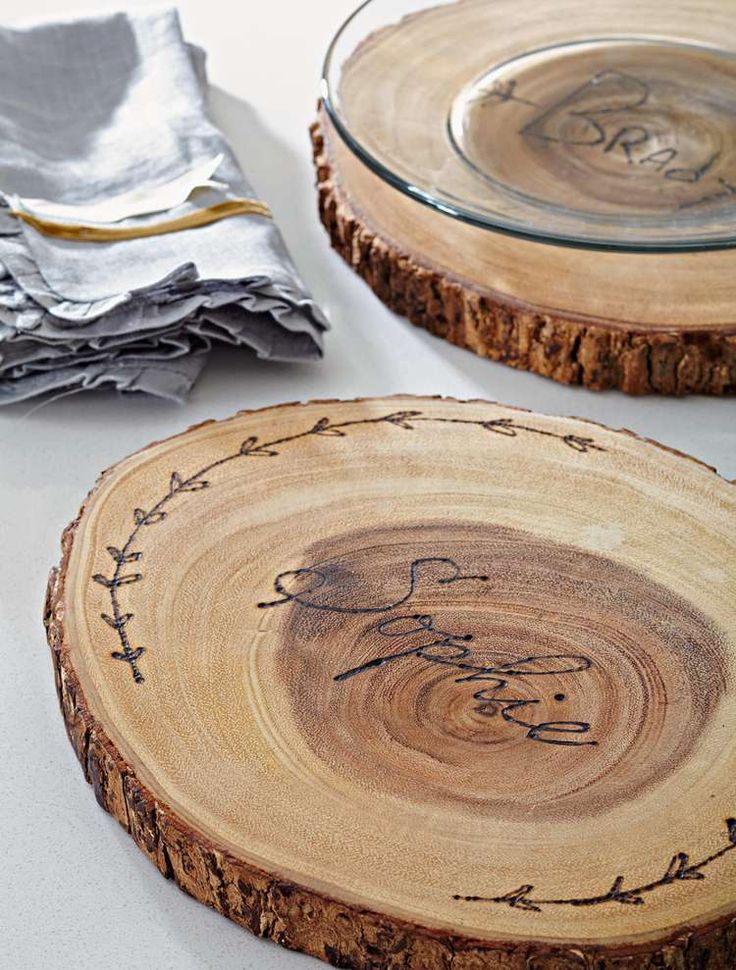 two wooden slices with designs on them sitting next to napkins and silverware plates