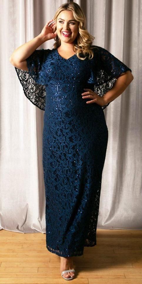 a woman standing in front of a curtain wearing a blue lace dress and matching heels