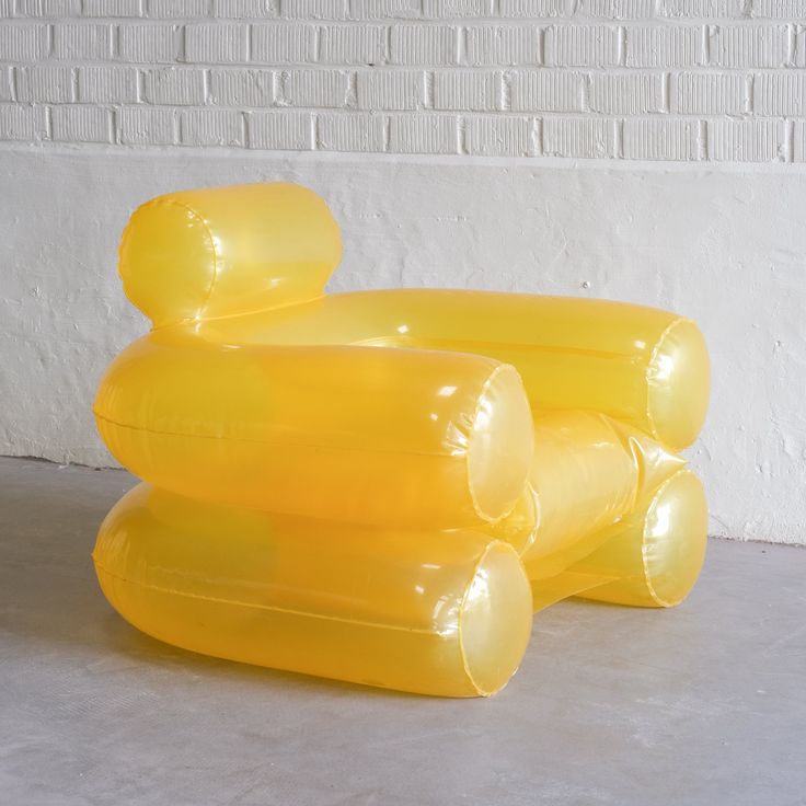 three yellow inflatable objects sitting on the ground next to a brick wall and floor