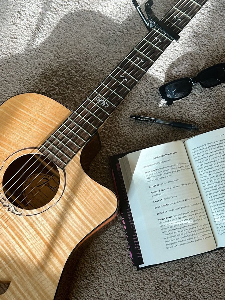 an open book and guitar laying on the floor