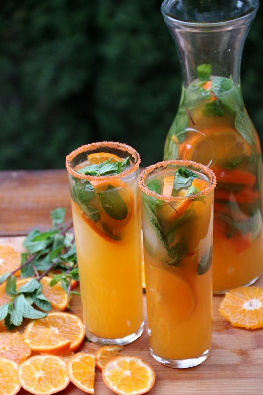 two glasses filled with orange juice and garnished with mint