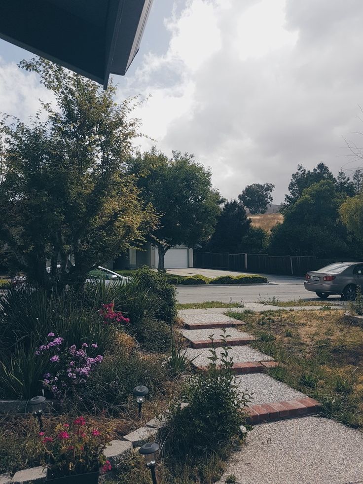 a car parked in front of a house next to a garden and driveway with stepping stones