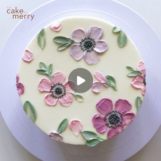 a white cake with pink and green flowers on it's side, sitting on a plate