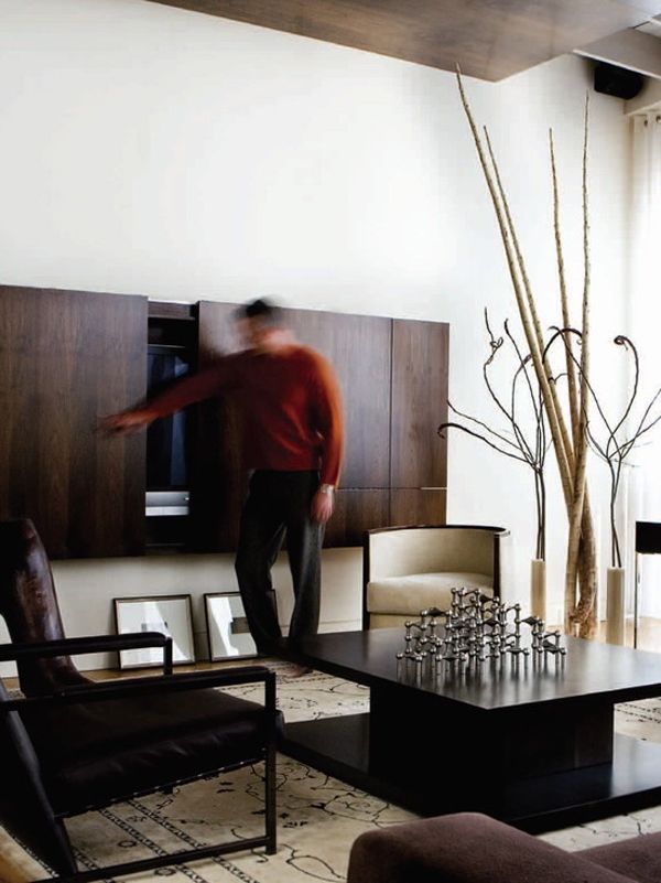 a man standing in the middle of a living room next to a table and chairs