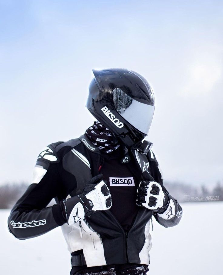 a person in black and white gear standing in the snow with their hands on his hips