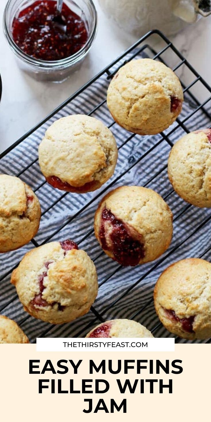 muffins filled with jam sitting on top of a cooling rack next to a jar of jam