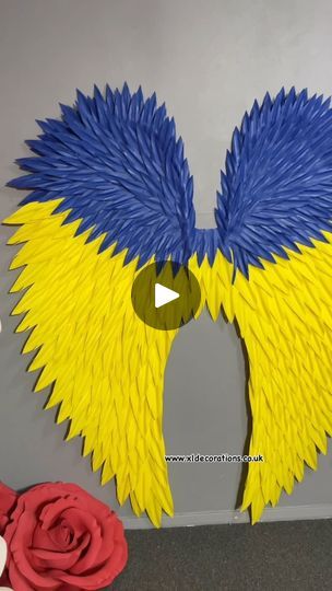 a large blue and yellow bird made out of paper with its wings spread wide open