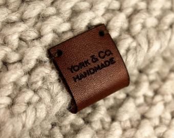 a close up of a brown label on a white knitted material with the words york & co handmade