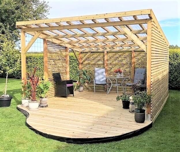 a wooden gazebo sitting in the middle of a lush green yard with potted plants