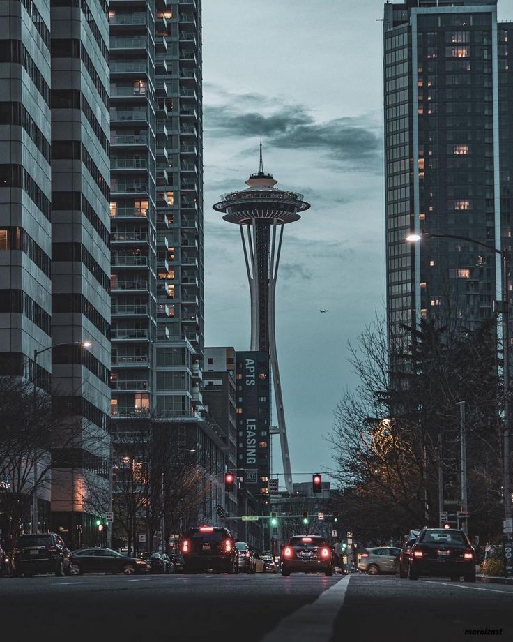 the space needle in seattle at night with cars driving on the street and tall buildings