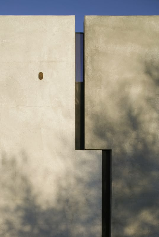 the side of a white building with a clock on it's face and trees in the background