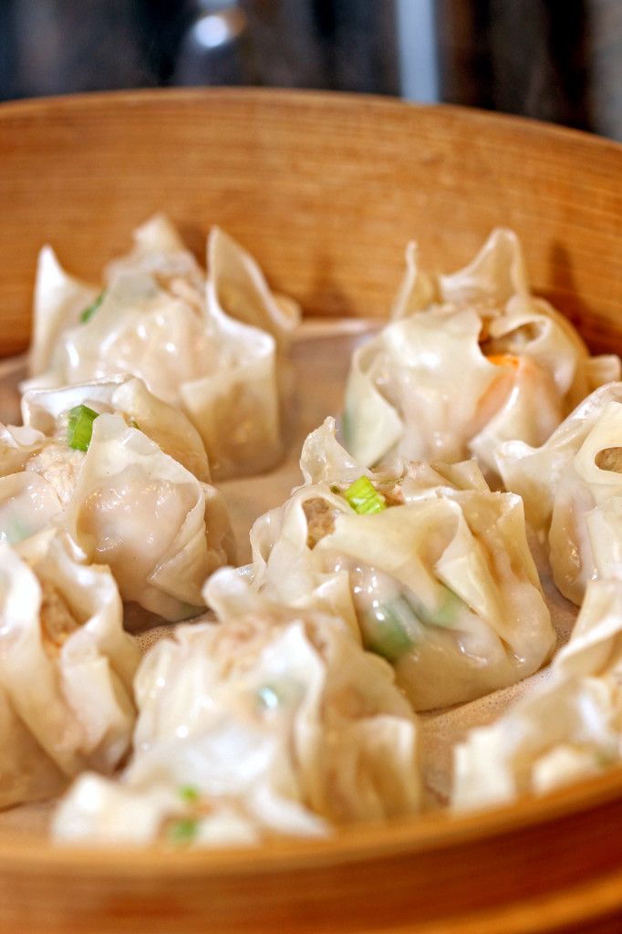 a wooden bowl filled with dumplings on top of a table