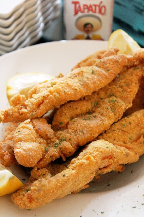 fried fish and lemon wedges on a white plate