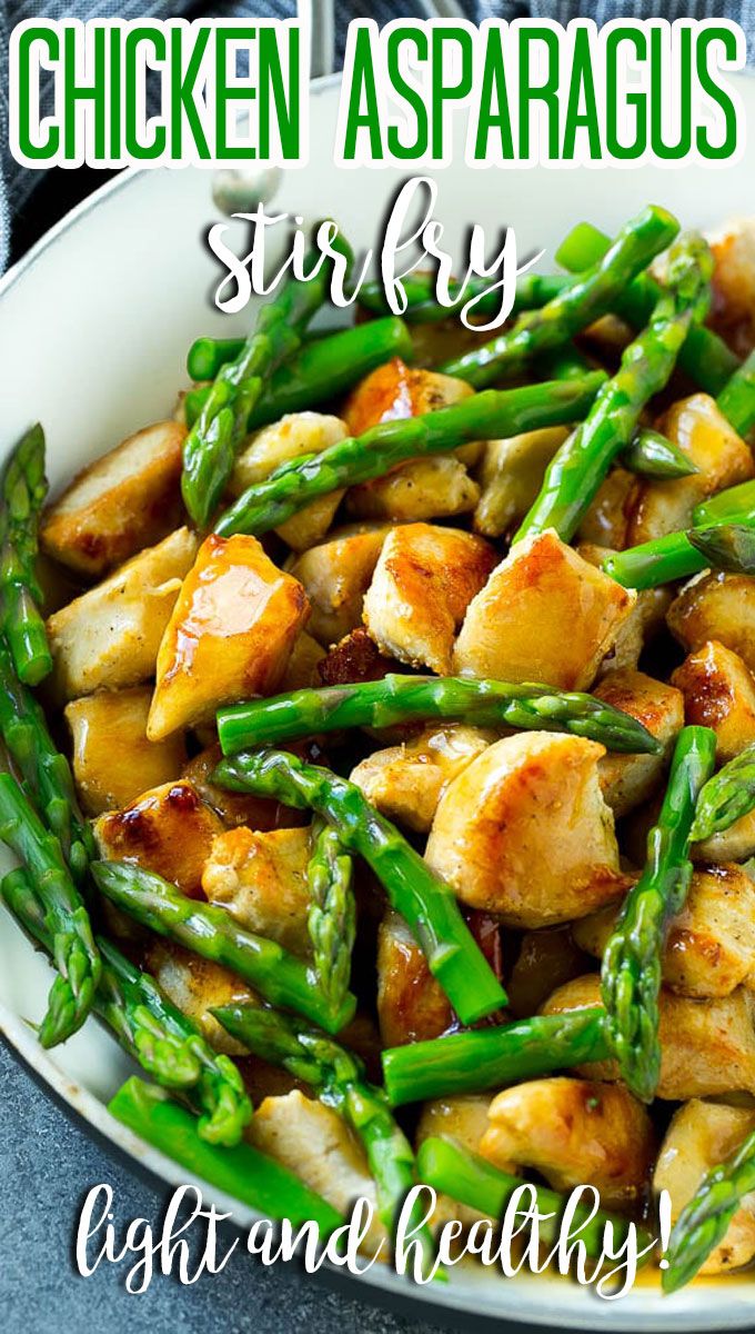 chicken and asparagus stir fry in a white bowl with green beans on the side