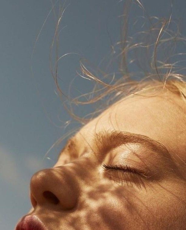 a close up of a child's face with the sky in the background