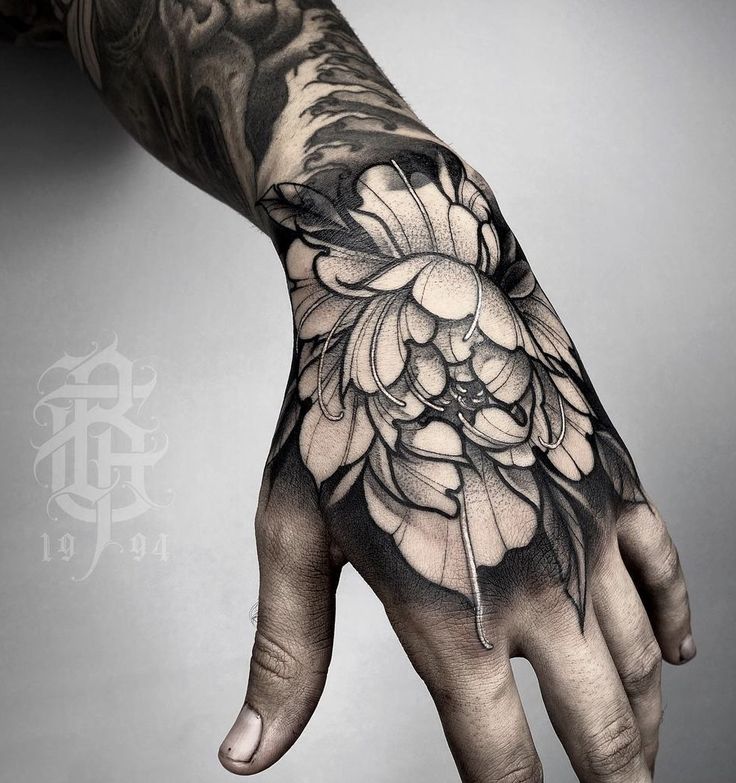 a man's hand with a flower tattoo on it and scissors in the middle