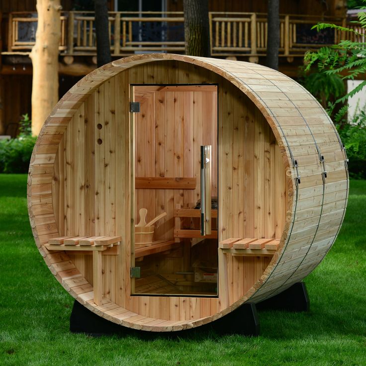 a wooden sauna in the middle of a yard next to a chair and potted plant