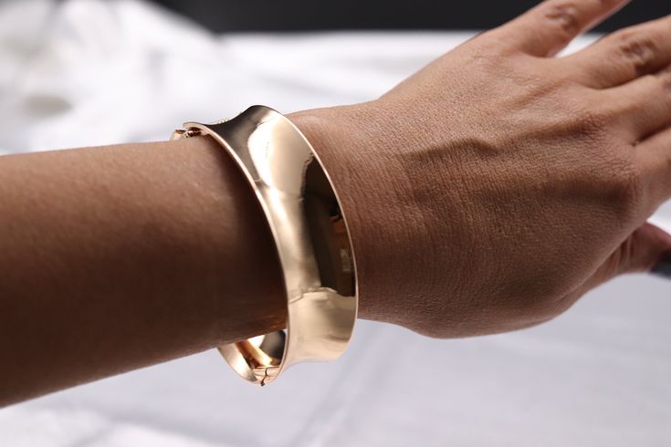 Elevate your wrist with our Gold Hinge Bracelet, a radiant accessory that seamlessly blends modern design with classic opulence. This bracelet, adorned with gleaming gold, is a statement piece that adds a touch of glamour to any ensemble, making it an essential for those who appreciate refined elegance. Size: 7 3/4 inches - Inner Diameter Closure: Bangle Hinge Bracelet Material: Brass with 18K Gold Plating Lead Free and Hypoallergenic Chic Gold-tone Metal Bangle, Chic Gold Metal Bangle Bracelet, Chic Rose Gold Metal Cuff Bracelet, Chic Rose Gold Bangle For Formal Occasions, Modern Gold-tone Bangle For Formal Occasions, Elegant Gold-tone Metal Cuff Bracelet, Modern Gold-tone Formal Bangle, Elegant Rose Gold Cuff Bracelet For Formal Occasions, Chic Rose Gold Bangle Bracelet