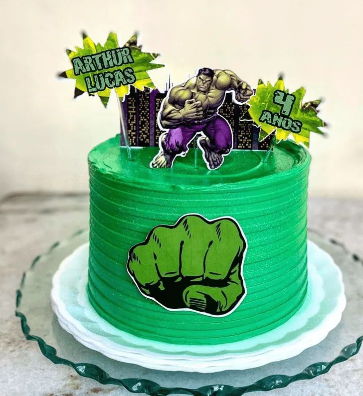 there is a green cake decorated with an image of the hulk on it and some stickers