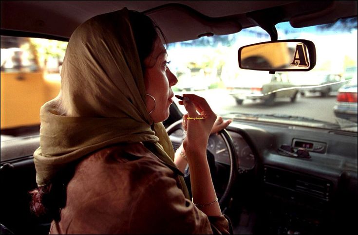 a woman sitting in the passenger seat of a car with her hand up to her mouth