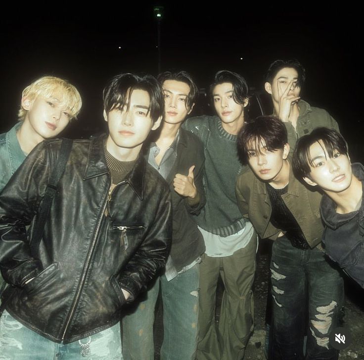 a group of young men standing next to each other in front of a dark background