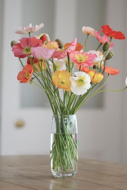 a glass vase filled with colorful flowers on top of a wooden table