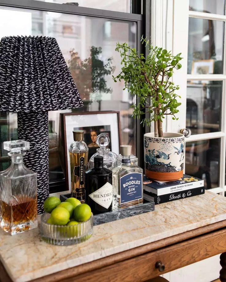 an assortment of liquors and other items on a counter in front of a window