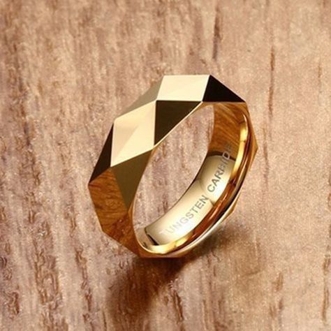 a gold ring with black and white diamonds on it sitting on a wooden table next to a wall