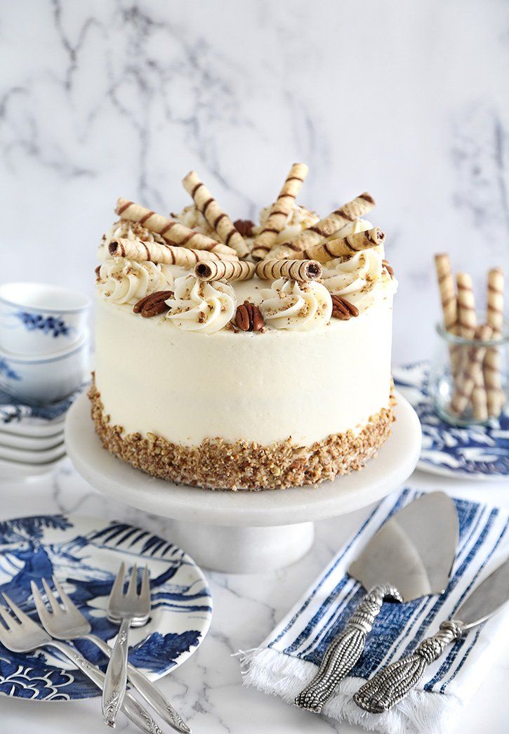 a cake with white frosting and cookies on top sitting on a plate next to silverware