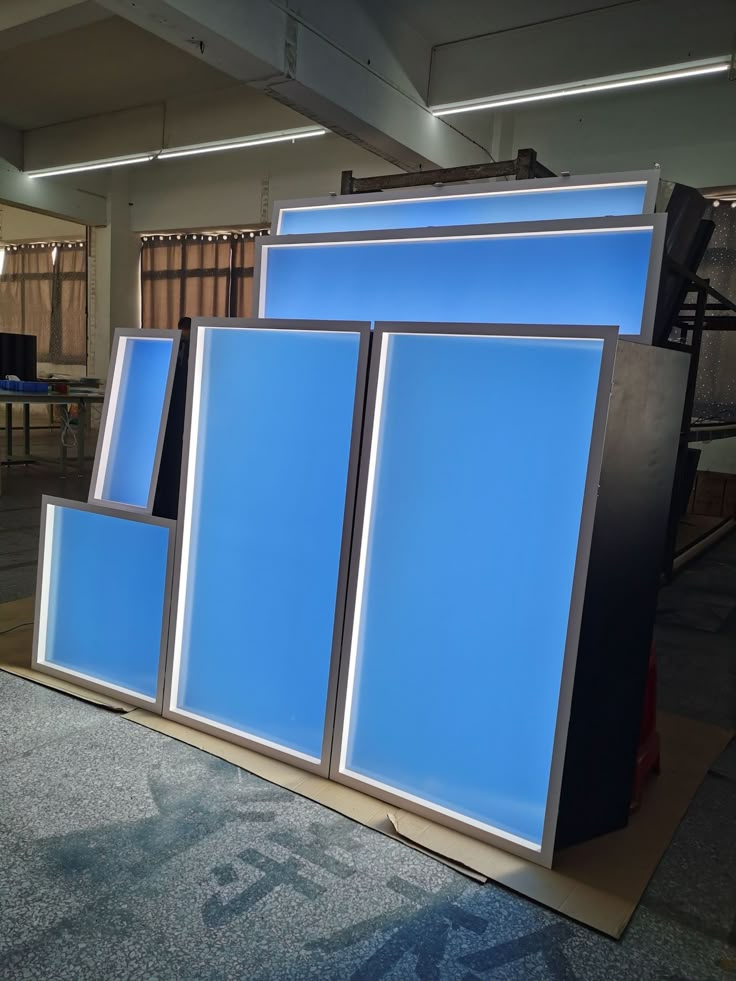 three large blue televisions sitting on top of a wooden stand in an office building