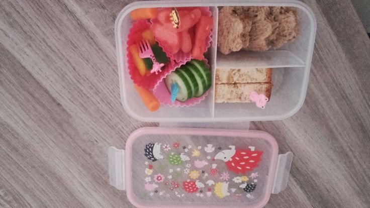 two plastic containers filled with food on top of a wooden floor