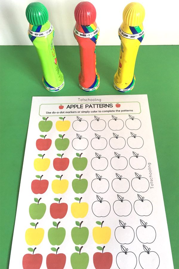 an apple pattern is on the table next to two pencils and a paper roll