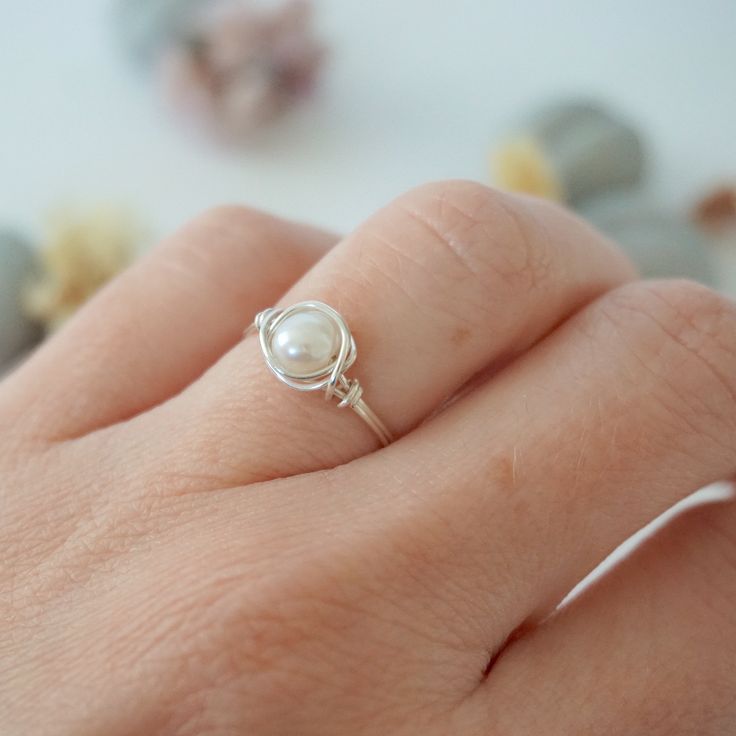 a woman's hand with a pearl ring on it